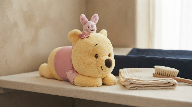 A Lovedline Sakura Winnie the Pooh plush on a linen shelf beside a soft brush